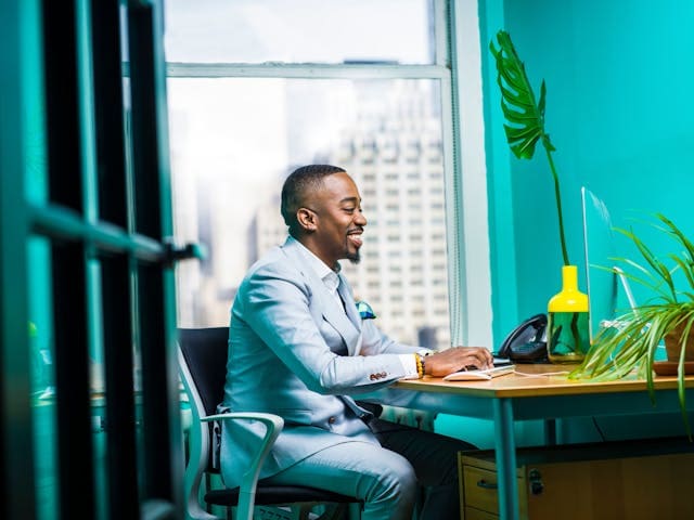 Profissional sorridente trabalhando no computador em um escritório iluminado, representando o domínio das soft skills mais valorizadas no mercado de trabalho.