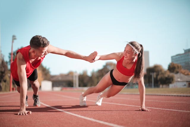 Duas pessoas treinando juntas em uma pista de corrida, simbolizando o desenvolvimento de soft skills como um treino de fortalecimento muscular.